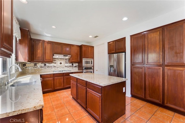 kitchen featuring tasteful backsplash, a kitchen island, stainless steel appliances, under cabinet range hood, and a sink