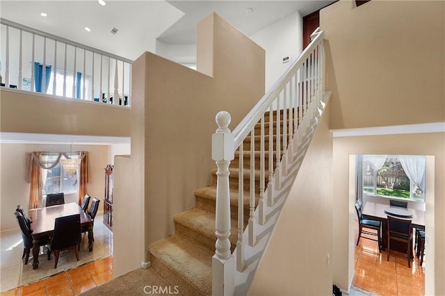 staircase featuring a high ceiling, plenty of natural light, and tile patterned floors