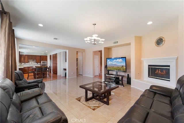 living room with baseboards, visible vents, a glass covered fireplace, an inviting chandelier, and recessed lighting