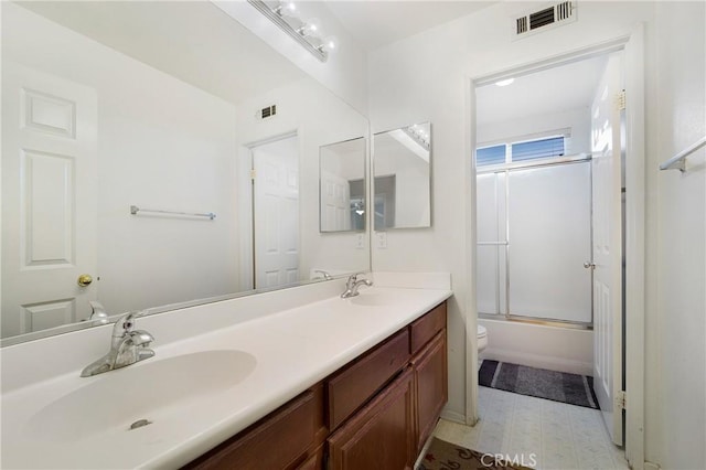 bathroom with visible vents, a sink, toilet, and double vanity