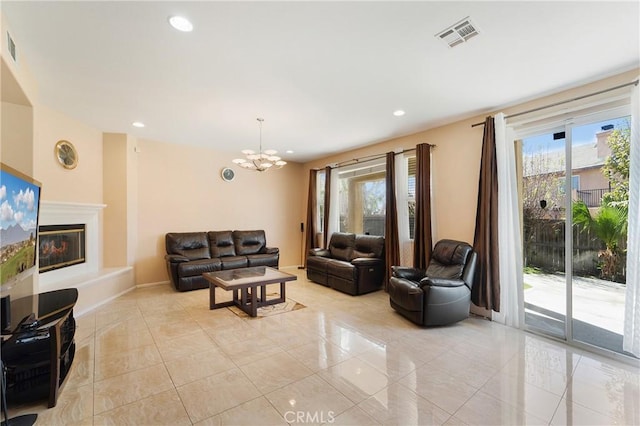 living area featuring light tile patterned flooring, recessed lighting, a notable chandelier, visible vents, and a glass covered fireplace