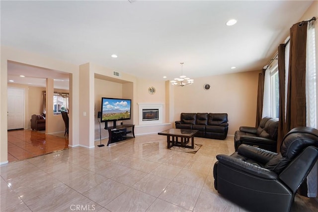 living area with baseboards, recessed lighting, a glass covered fireplace, and a healthy amount of sunlight