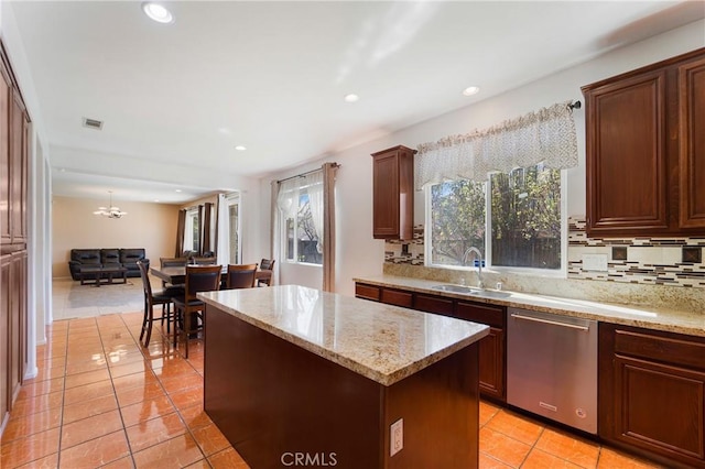 kitchen featuring a kitchen island, backsplash, open floor plan, stainless steel dishwasher, and a sink