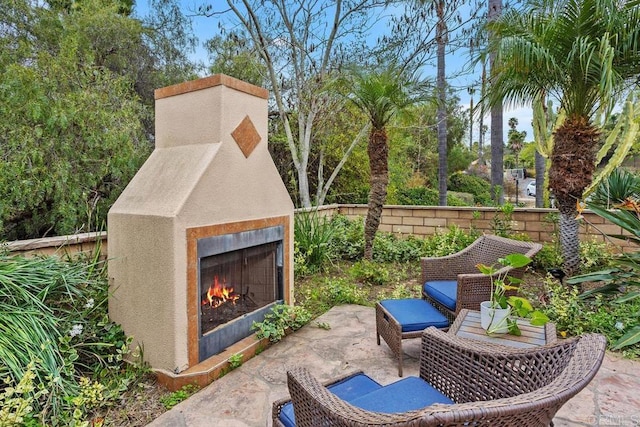 view of patio / terrace featuring a warm lit fireplace and fence