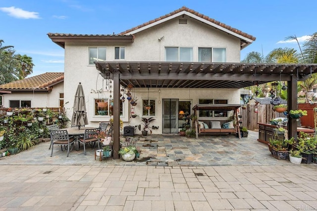 rear view of house featuring stucco siding, fence, a patio area, a pergola, and outdoor dining space