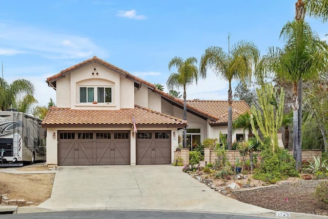 mediterranean / spanish-style house featuring a tile roof, driveway, and stucco siding