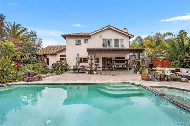 rear view of house featuring a patio, a pool with connected hot tub, a tiled roof, stucco siding, and a pergola