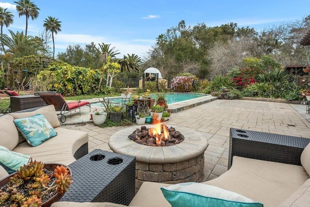 pool featuring a patio area and an outdoor living space with a fire pit