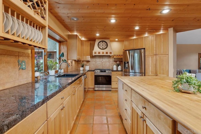 kitchen featuring tasteful backsplash, wooden ceiling, custom range hood, stainless steel appliances, and a sink