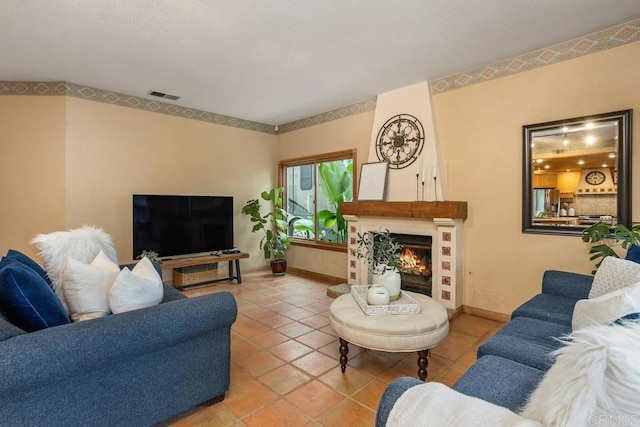 living area with a large fireplace, tile patterned floors, visible vents, and baseboards