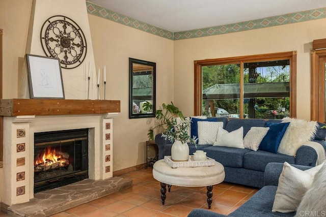 tiled living area featuring a glass covered fireplace and baseboards