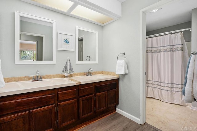 bathroom featuring double vanity, curtained shower, a sink, and wood finished floors