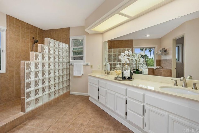 bathroom with double vanity, tile patterned flooring, a walk in shower, and a sink