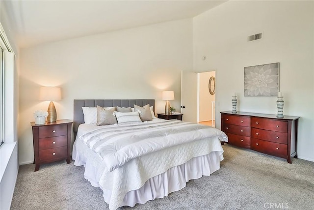 bedroom featuring high vaulted ceiling, visible vents, and light colored carpet