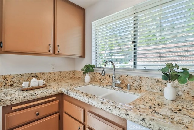 kitchen featuring light stone counters and a sink