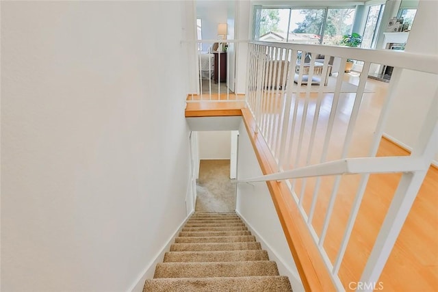 staircase with carpet, a fireplace, and baseboards