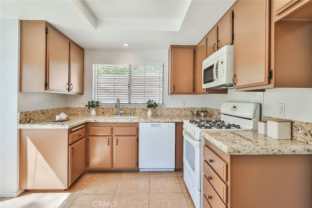 kitchen featuring white appliances, light tile patterned floors, light stone countertops, a tray ceiling, and a sink