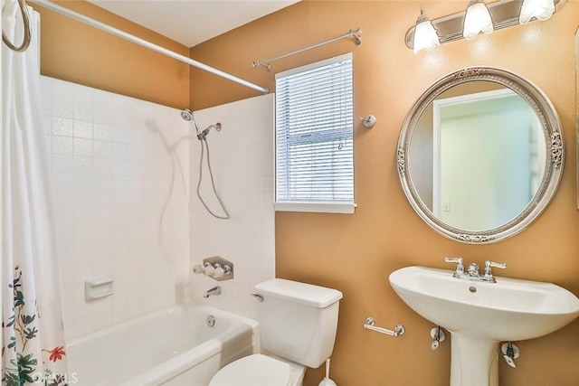 bathroom featuring a sink, shower / bath combo with shower curtain, and toilet