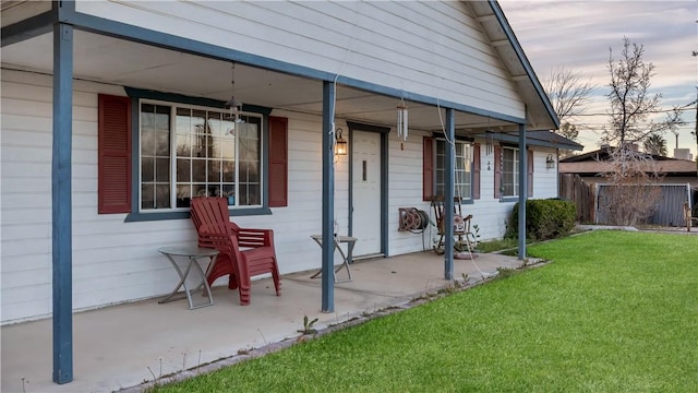 exterior entry at dusk with fence and a lawn