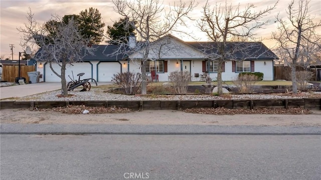 ranch-style home with driveway, an attached garage, and fence