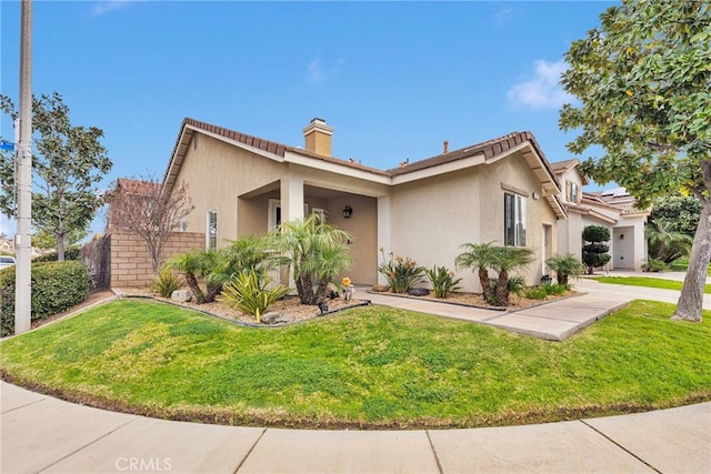 view of front of house with a front yard, a chimney, and stucco siding