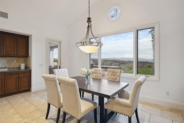 dining room with light tile patterned floors, visible vents, baseboards, and high vaulted ceiling