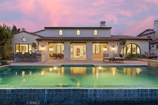 back of house featuring a patio area, a tiled roof, and stucco siding