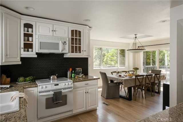 kitchen with white appliances, light wood finished floors, decorative backsplash, glass insert cabinets, and white cabinetry