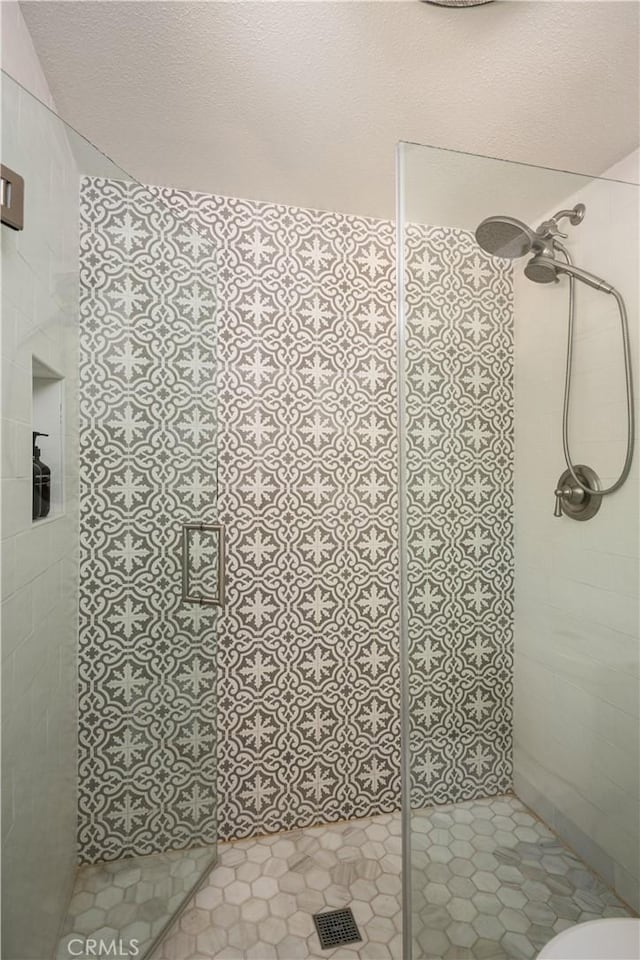 full bathroom with a stall shower, a textured ceiling, and toilet