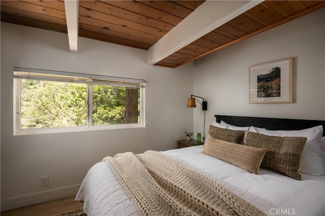 bedroom with vaulted ceiling with beams, wooden ceiling, wood finished floors, and baseboards