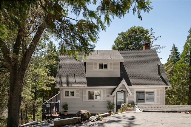 view of front of house with a shingled roof and a chimney