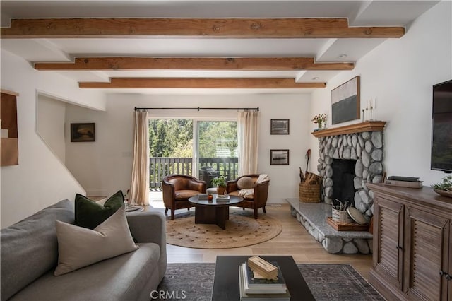 living room with a fireplace, beamed ceiling, and light wood finished floors