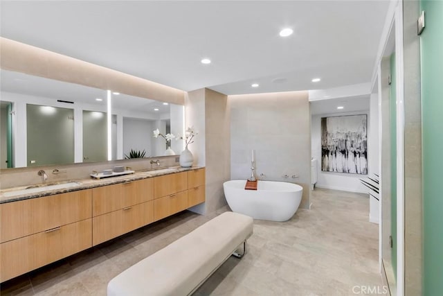 bathroom featuring a freestanding tub, double vanity, recessed lighting, and a sink