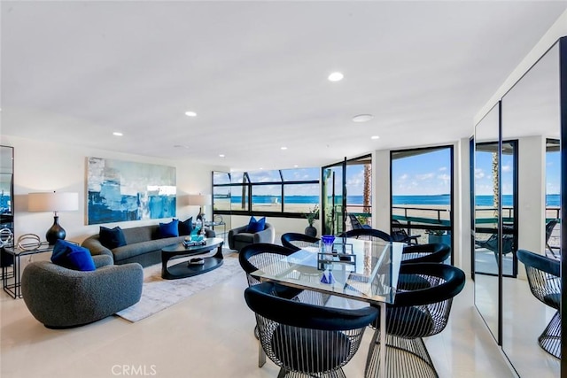 living room with a water view, a wealth of natural light, recessed lighting, and a wall of windows