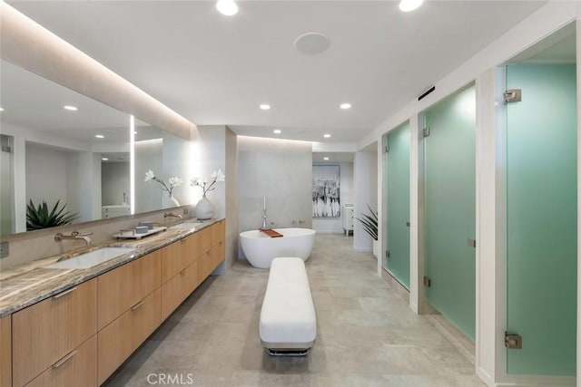 full bath with a soaking tub, double vanity, recessed lighting, a sink, and a stall shower