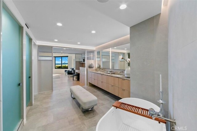 bathroom with a freestanding tub, double vanity, recessed lighting, and a sink