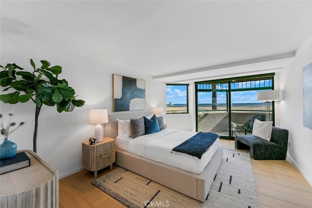 bedroom with baseboards, access to exterior, and wood finished floors
