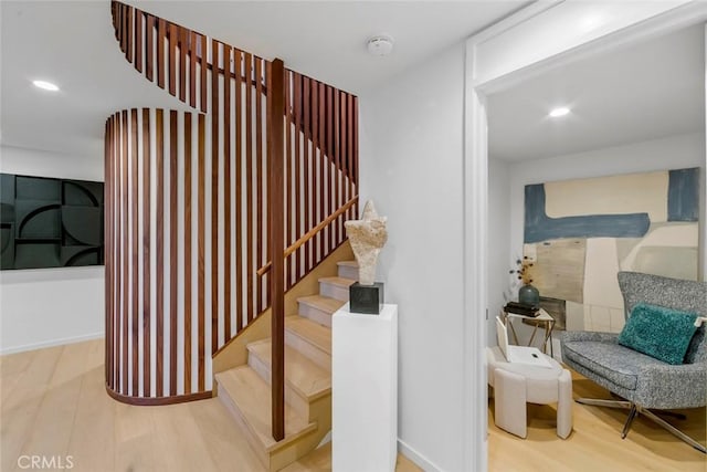 stairway featuring baseboards, wood finished floors, and recessed lighting