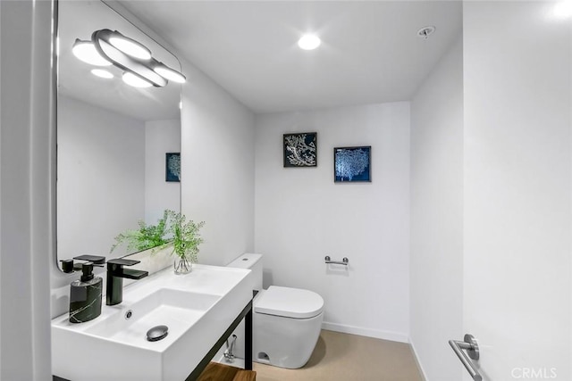 bathroom with toilet, vanity, and baseboards