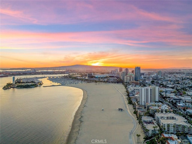 aerial view at dusk featuring a beach view, a water view, and a view of city