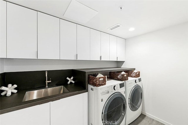 laundry room with washing machine and clothes dryer, visible vents, baseboards, a sink, and cabinet space