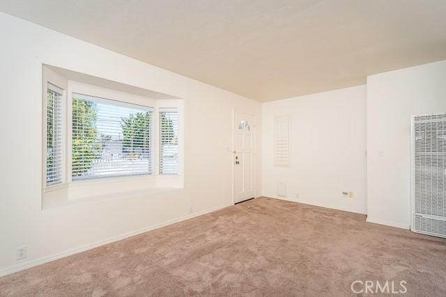 carpeted spare room with a heating unit