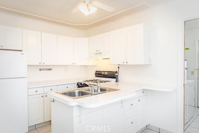 kitchen with range with gas cooktop, freestanding refrigerator, a peninsula, under cabinet range hood, and a sink