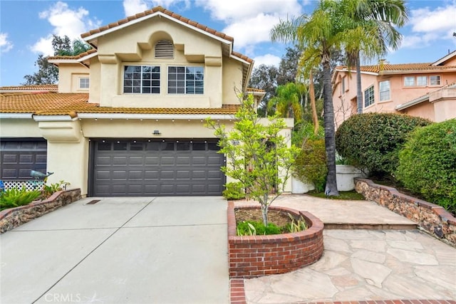 mediterranean / spanish house featuring concrete driveway, an attached garage, and stucco siding