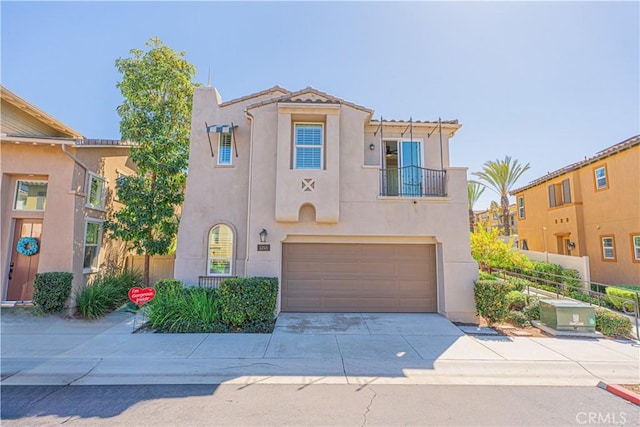 mediterranean / spanish-style home featuring fence, concrete driveway, stucco siding, a balcony, and a garage