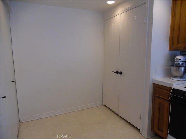 kitchen with brown cabinetry, recessed lighting, light countertops, and baseboards