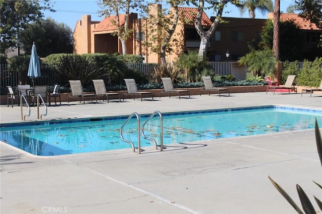 pool with a patio area and fence