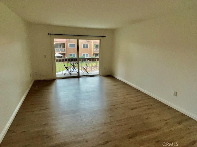 spare room featuring baseboards and wood finished floors