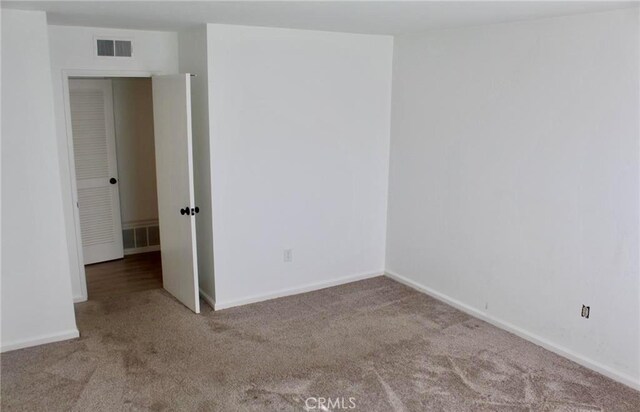 empty room featuring carpet floors, baseboards, and visible vents