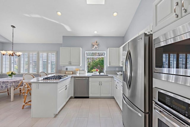 kitchen featuring stainless steel appliances, a wealth of natural light, light countertops, and a peninsula